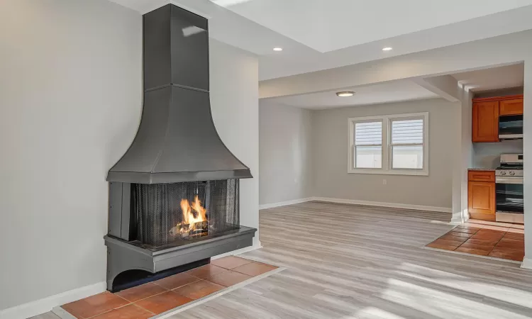 Unfurnished living room featuring a multi sided fireplace and light hardwood / wood-style flooring