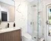 Bathroom with vanity, toilet, a shower with door, and backsplash