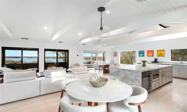 Dining area featuring wooden ceiling, a water view, sink, light hardwood / wood-style flooring, and vaulted ceiling with beams