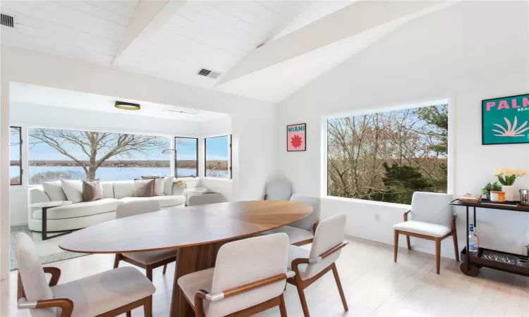 Dining room featuring lofted ceiling with beams, a water view, and light wood-type flooring