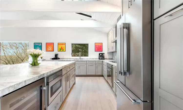 Kitchen featuring lofted ceiling with beams, stainless steel appliances, wine cooler, and plenty of natural light