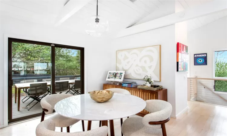 Dining space with vaulted ceiling with beams, light wood-type flooring, and a wealth of natural light