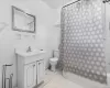 Full bathroom featuring vanity, tile patterned flooring, toilet, ornamental molding, and tile walls