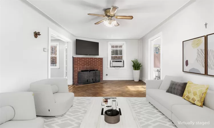 Living room with a brick fireplace, parquet floors, cooling unit, and ceiling fan