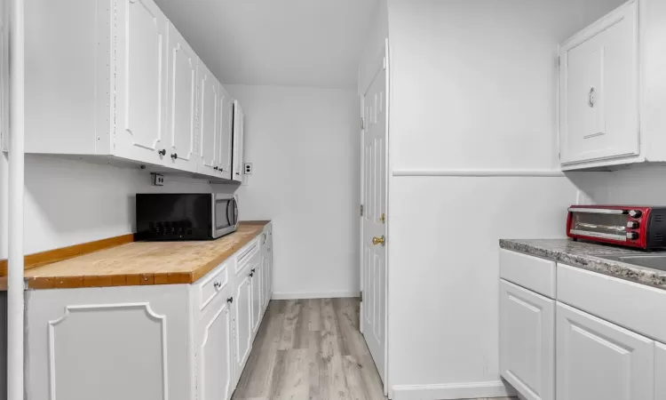 Kitchen with white cabinetry, light hardwood / wood-style flooring, and wooden counters