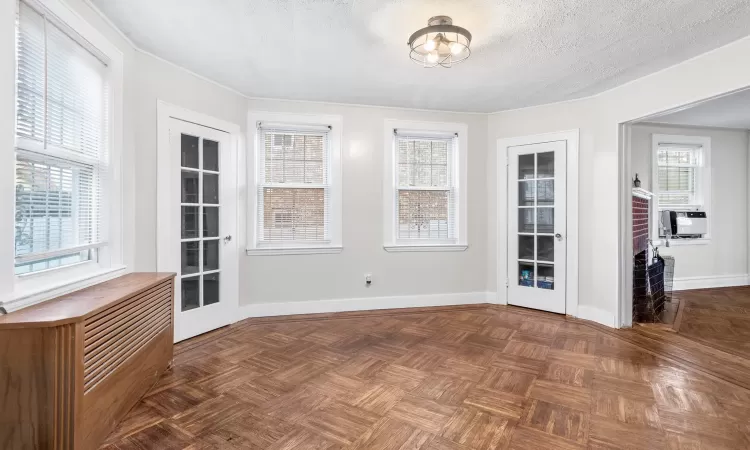 Spare room featuring french doors, dark parquet flooring, plenty of natural light, and a textured ceiling