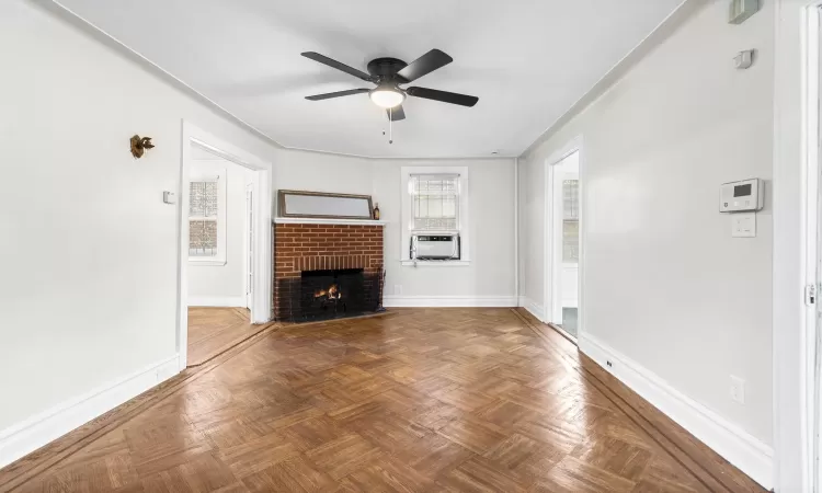 Unfurnished living room featuring ceiling fan, cooling unit, dark parquet flooring, and a brick fireplace