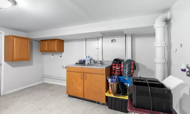 Basement with light tile patterned floors and sink