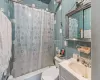 Full bathroom with tasteful backsplash, toilet, shower / tub combo with curtain, vanity, and tile walls