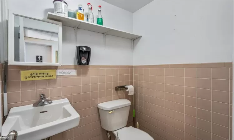 Bathroom featuring sink, tile walls, and toilet