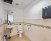 Bathroom featuring a drop ceiling, tile patterned floors, sink, toilet, and tile walls