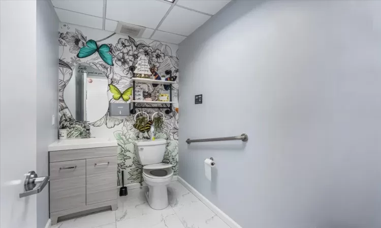 Bathroom featuring a paneled ceiling, vanity, and toilet