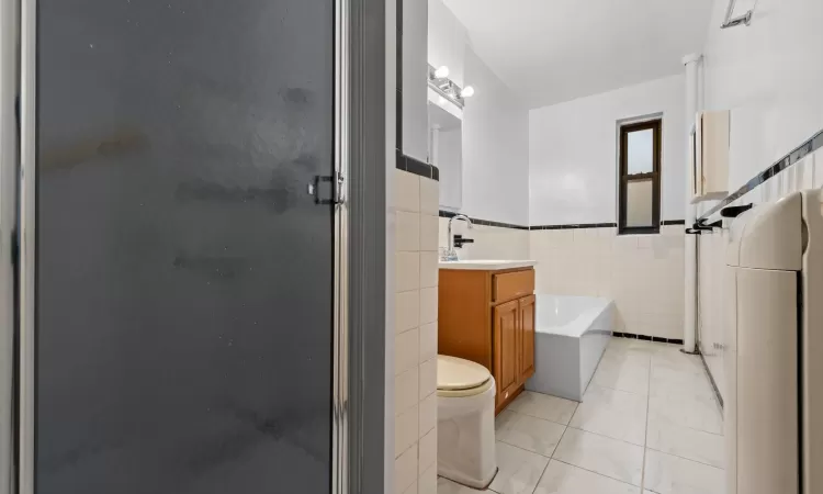 Bathroom featuring vanity, a bath, toilet, and tile walls