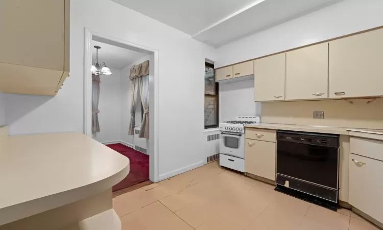 Kitchen featuring dishwasher, cream cabinets, sink, stainless steel fridge, and white range with gas cooktop