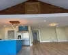 Kitchen with stainless steel fridge, vaulted ceiling, blue cabinetry, hardwood / wood-style flooring, and decorative light fixtures