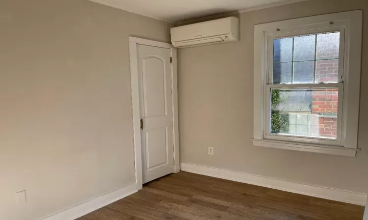 Spare room featuring an AC wall unit, crown molding, and dark hardwood / wood-style flooring