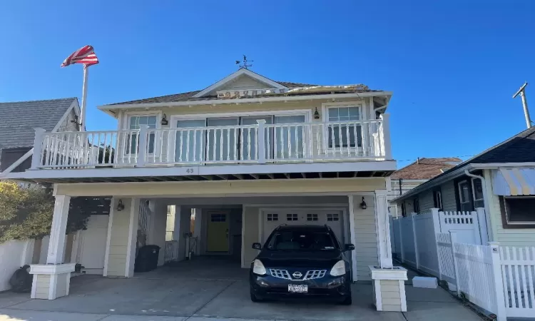 View of front of house with a balcony, a garage, and a carport