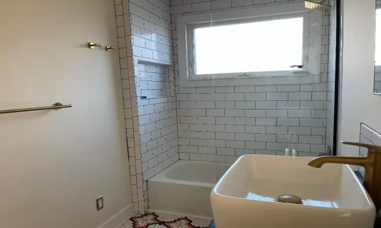 Bathroom featuring tile patterned flooring, tiled shower / bath, plenty of natural light, and sink