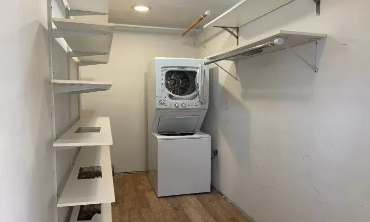 Large walk-in-closet with washer/dryer featuring hardwood / wood-style floors