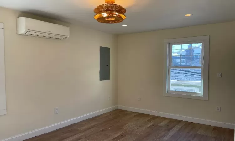 bedroom featuring large walk in closet, split unit, and hardwood / wood-style flooring