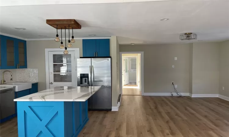 Kitchen featuring a center island, stainless steel appliances, blue cabinets, and dark hardwood / wood-style floors