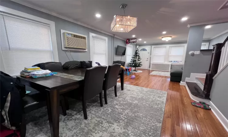 Dining area featuring radiator, crown molding, a wall mounted air conditioner, and light wood-type flooring