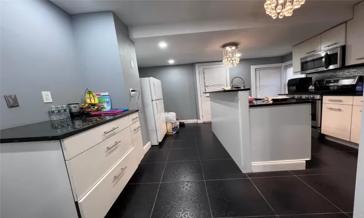 Kitchen featuring white cabinets, pendant lighting, stainless steel appliances, and a chandelier