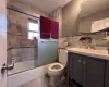 Full bathroom with backsplash, bath / shower combo with glass door, vanity, tile walls, and toilet