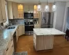 Kitchen featuring appliances with stainless steel finishes, a center island, decorative light fixtures, and light hardwood / wood-style floors