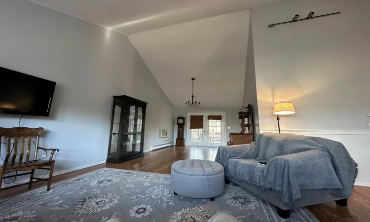 Living room featuring lofted ceiling, dark wood-type flooring, and french doors