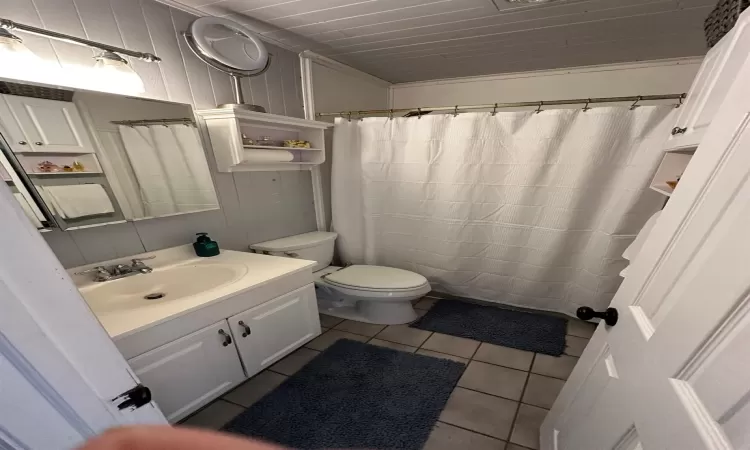 Bathroom featuring tile patterned floors, vanity, ornamental molding, and toilet