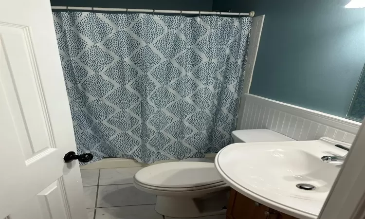 Bathroom featuring toilet, curtained shower, and sink