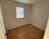 Empty room featuring baseboard heating and dark wood-type flooring