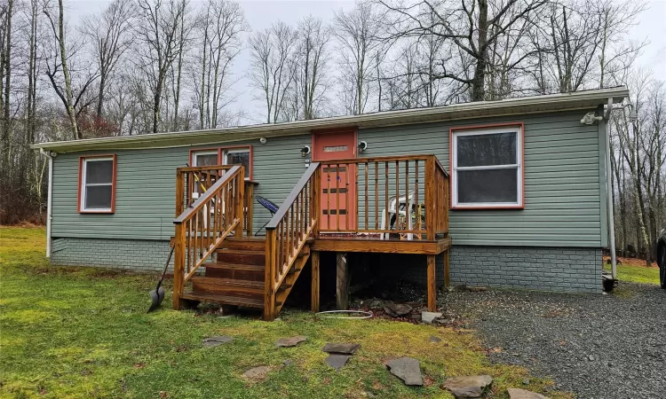 Back of property featuring a deck and a lawn