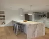 Kitchen with light hardwood / wood-style floors, a breakfast bar area, built in features, pendant lighting, and white cabinets