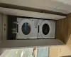 Laundry area featuring a skylight, stacked washing maching and dryer, and hardwood / wood-style flooring