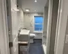 Bathroom featuring vanity, a baseboard heating unit, tile walls, tile patterned flooring, and toilet