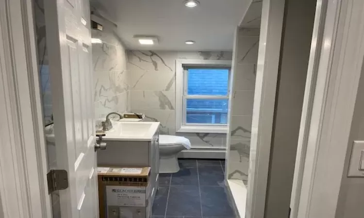 Bathroom featuring vanity, a baseboard heating unit, tile walls, tile patterned flooring, and toilet