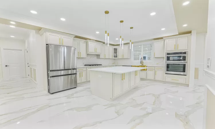 Kitchen featuring decorative backsplash, ornamental molding, stainless steel appliances, decorative light fixtures, and a center island