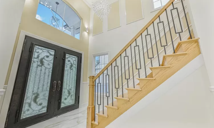 Entrance foyer with a chandelier, a high ceiling, and french doors