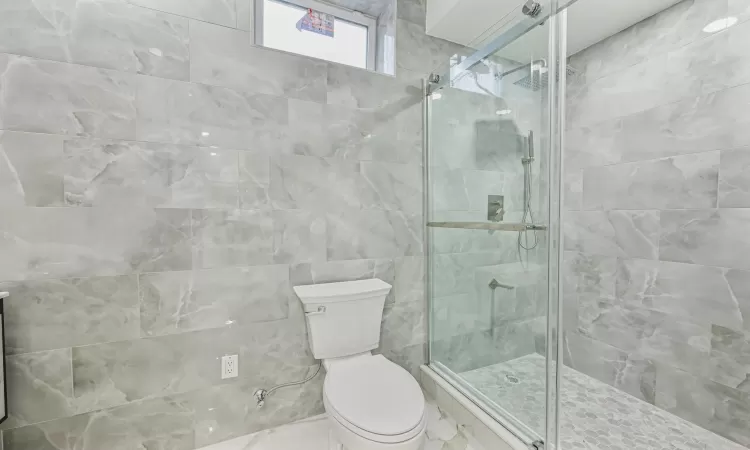 Bathroom with a shower with door, vanity, and toilet