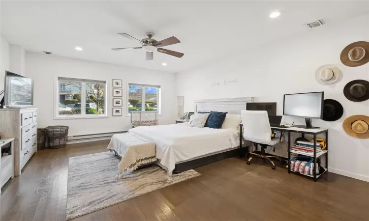 Bedroom with dark hardwood / wood-style floors, ceiling fan, and a baseboard heating unit