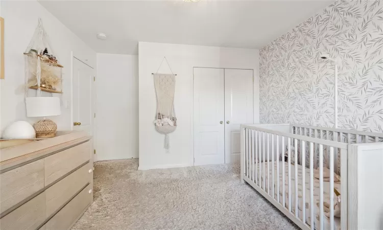 Bedroom with carpet flooring, a crib, and a closet