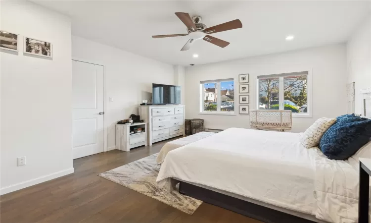 Bedroom with a baseboard heating unit, ceiling fan, and dark wood-type flooring