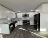 Kitchen featuring backsplash, dark wood-type flooring, sink, black appliances, and white cabinetry