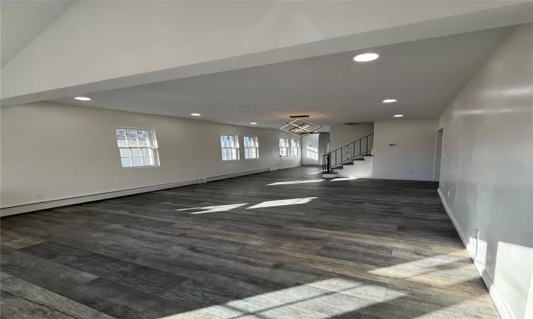 Front living room with inviting chandelier, dark wood-type flooring, and vaulted ceiling.