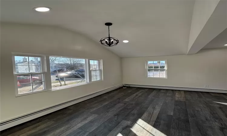 Entry with inviting chandelier, dark wood-type flooring, and vaulted ceiling.