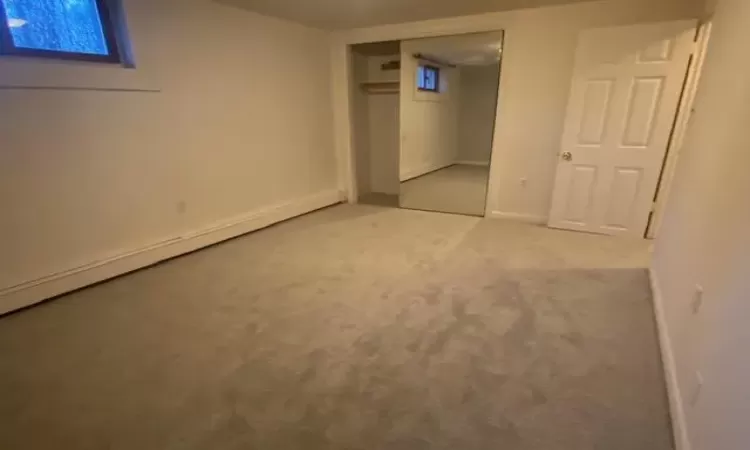 Unfurnished bedroom featuring carpet flooring, a baseboard radiator, and a closet