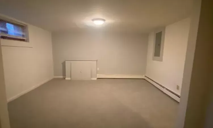 Basement featuring electric panel, carpet floors, and a baseboard radiator