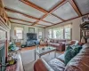 Living room with a brick fireplace, ornamental molding, coffered ceiling, wooden walls, and hardwood / wood-style flooring